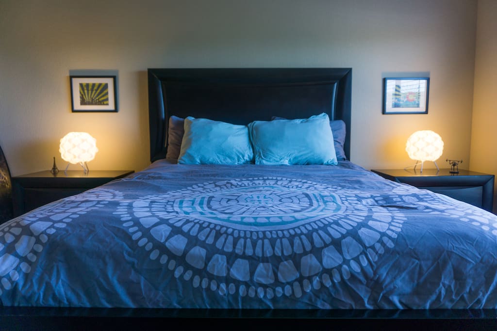 Luxury queen bed with plenty of pillows and power plugs on both side.