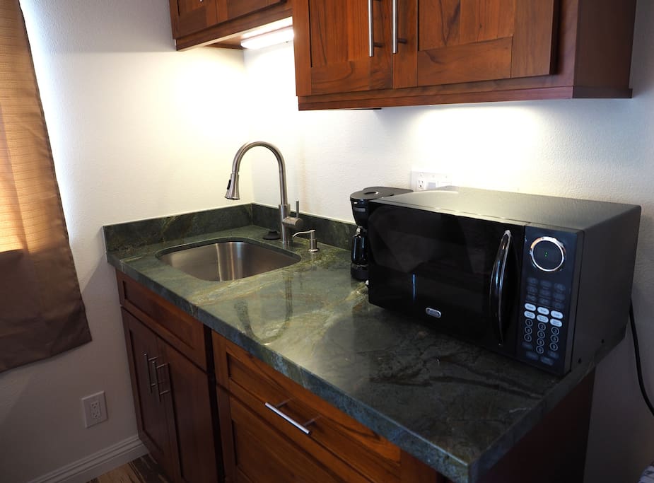 Kitchenette includes coffee maker, microwave, kitchen sink with disposal, compact refrigerator, portable butane gas burner, and utensils, dishes, and pots and pans for cooking,