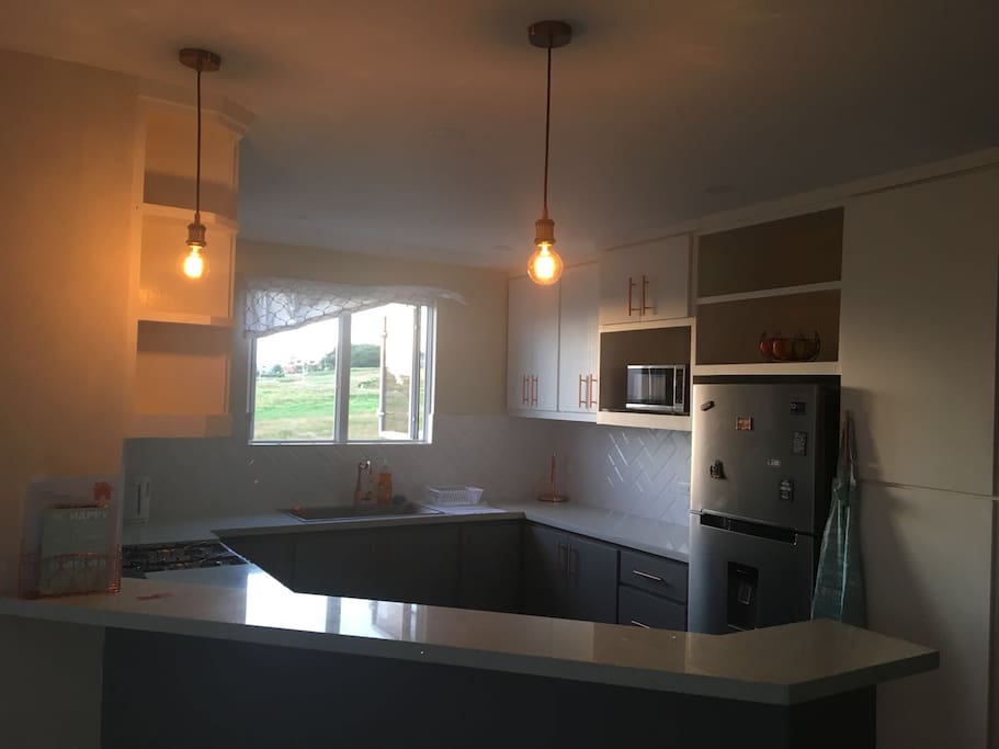 Kitchen with stove, fridge, microwave, kettle, pots and pans, crockery, cutlery and more