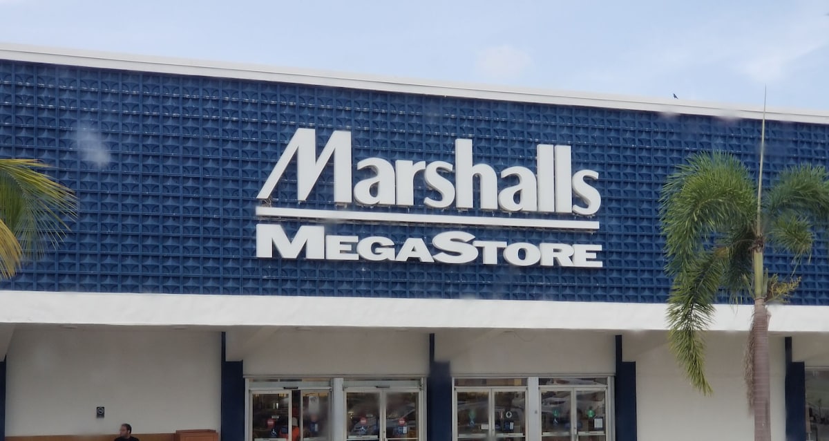 The exterior of a Marshalls MegaStore is displayed, featuring a large blue wall with the store's name prominently featured in white lettering. Palm trees are visible in the foreground, offering a glimpse of a warm, tropical environment.