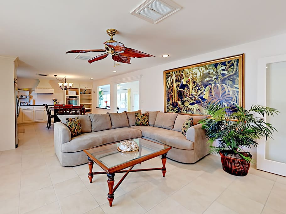 Spacious open-concept living room with plush sectional sleeper sofa and tropical artwork.