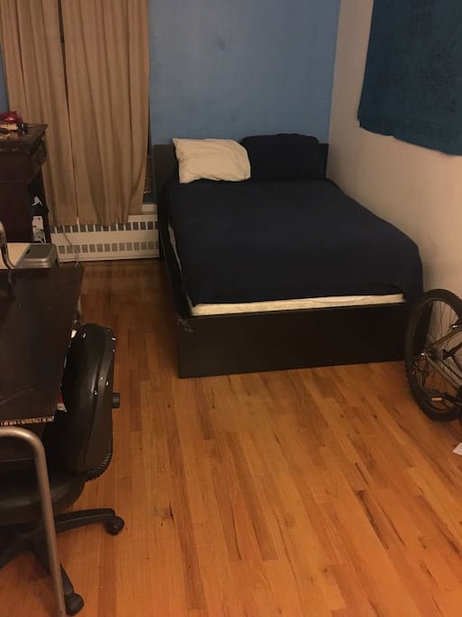 View of the bed and desk in the private bedroom.