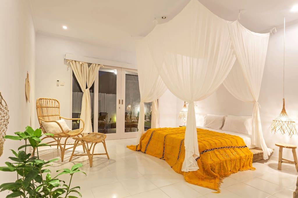 comfortable bed with 4 pillows and a unique mosquito net