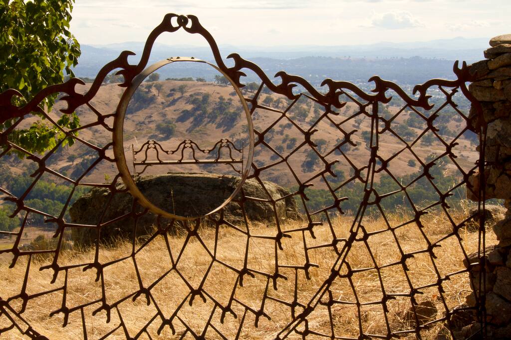 One of many sculptures. Gate with a bench perched on a rock beyond.