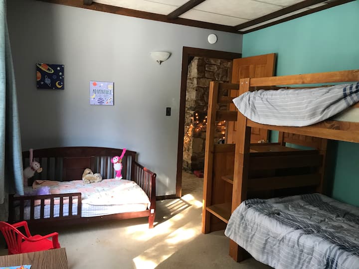 Na katu se nalazi dječja soba s krevetom na kat i dječjim krevetom. 