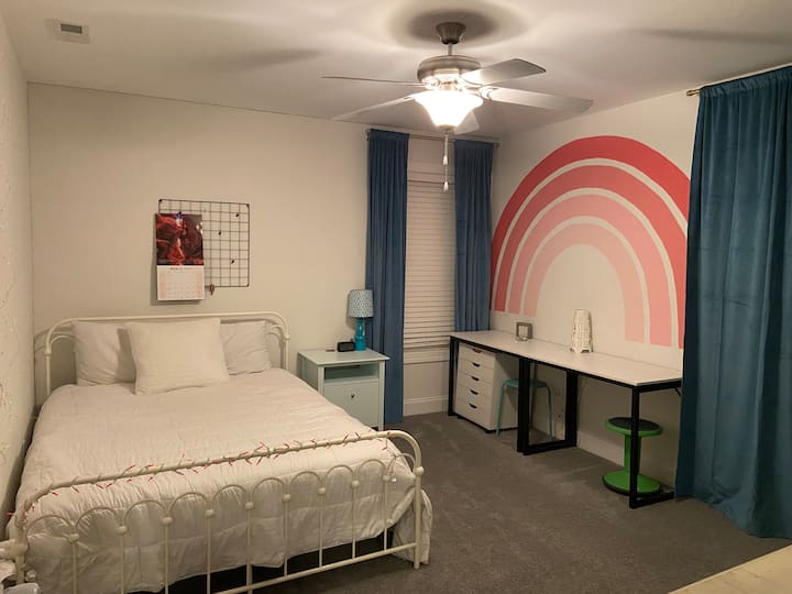 卧室配有标准双人床、书桌、吊扇和墙上彩虹壁画 