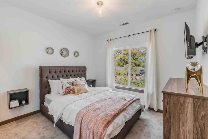 Chumba cha kulala cha malkia kilicho na godoro la kifahari, quilts na blanketi.  Dirisha lenye nafasi kubwa huweka chumba kikiwa safi na angavu. Roshani maridadi zinazoelea, televisheni na koni ya droo nyingi ni sehemu ya chumba. Limewekwa zulia na linaendelea kuwa nadhifu na safi.  