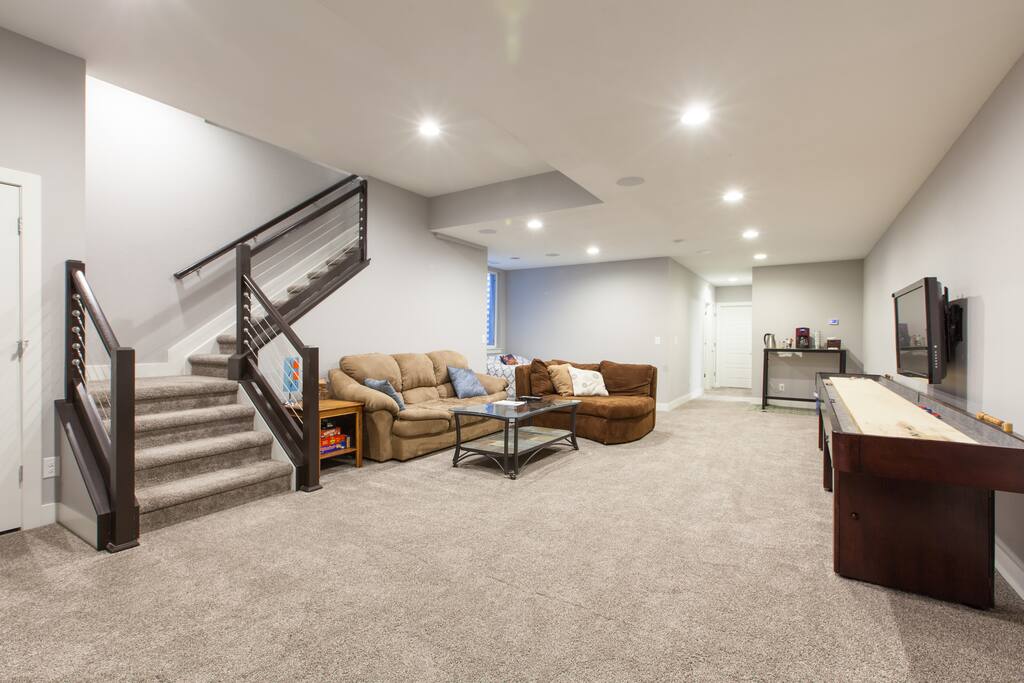 Spacious and private basement living room with shuffleboard table, TV, games and more.
