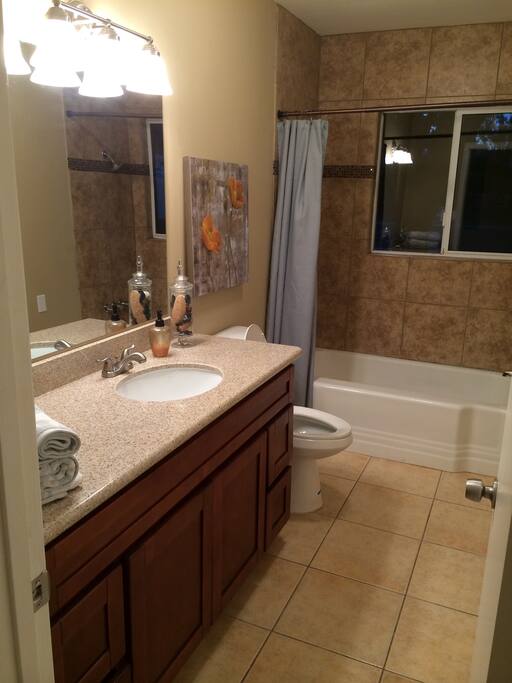 Guest bathroom with bath tub, shower, granite countertops, tiled floor and huge storage closet.