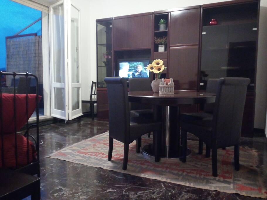 soggiorno con tavolo e sedie con tv e divano letto 1 piazza