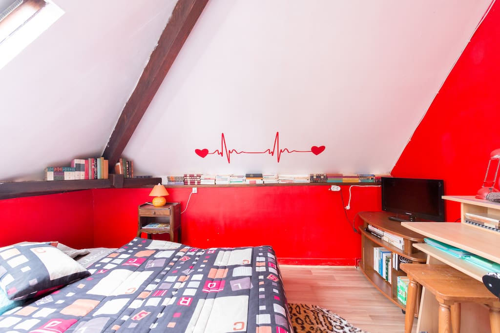 la même chambre rouge avec sa télé et son bureau