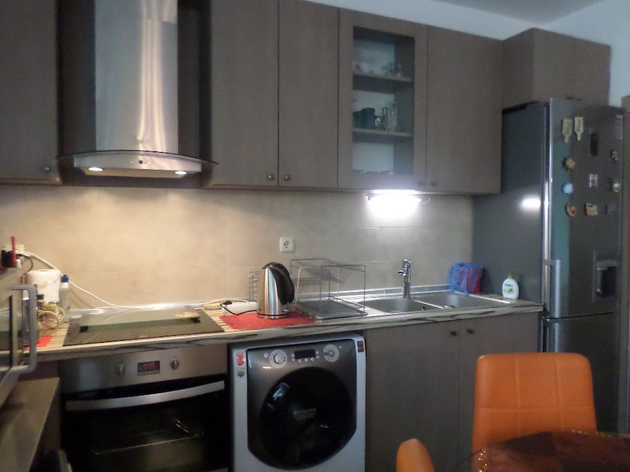 Kitchen with double basin, extractor above ceramic top, oven, large fridge/ frizzer and water dispenser, microwave, toaster
