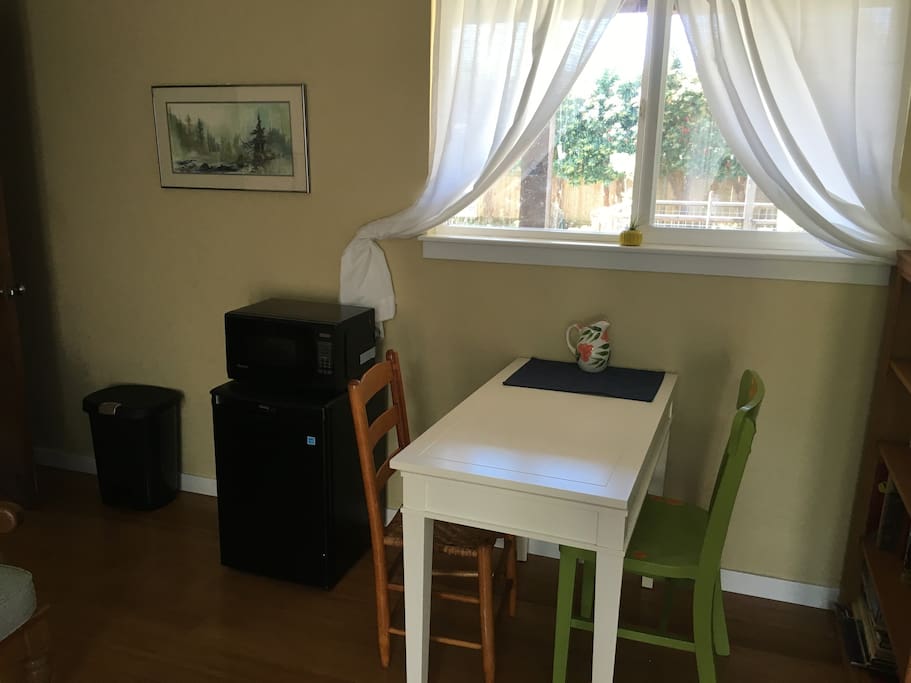 Eating area with a mini fridge, microwave, coffee maker, hot water kettle, dishes, and silverware.