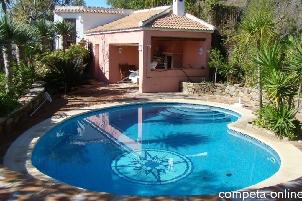 Blick über den Pool auf das Gästehäuschen und den überdachten Grillbereich