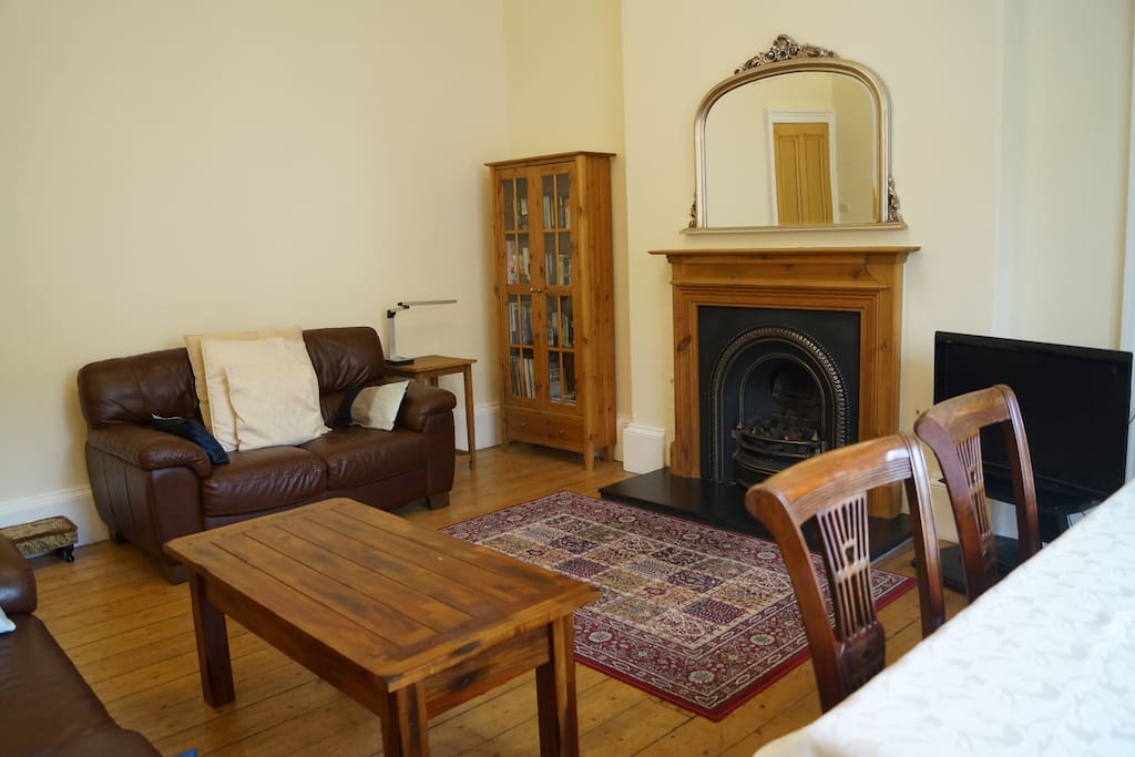 Living room with view to private garden belonging to flat. 2 sofas, TV, DVD player, gas fireplace, dining table, period features.