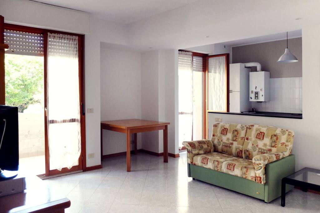 Soggiorno luminosissimo con divano letto, televisione e terrazzino.