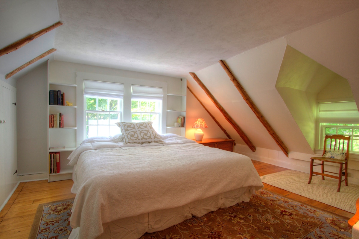 Habitación de invitados gris claro con cama tamaño king y vigas originales