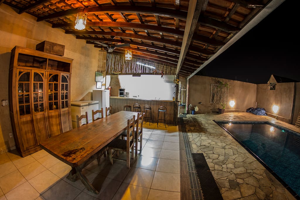 Mesa para refeições, cozinha ao fundo e à direita a piscina