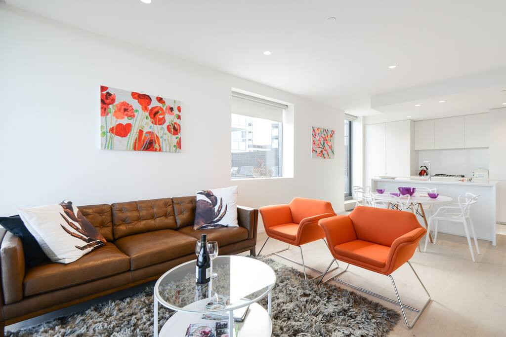 The expansive living room has a three seater leather couch, and separate lounge chairs for two