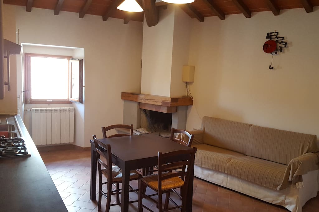 Cucina con tavolo, divano e camino