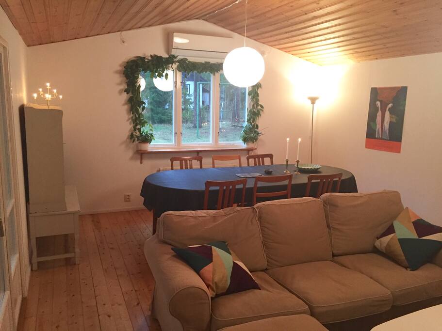Vardagsrum med matbord med plats för 10 personer, två soffor framför spisen.