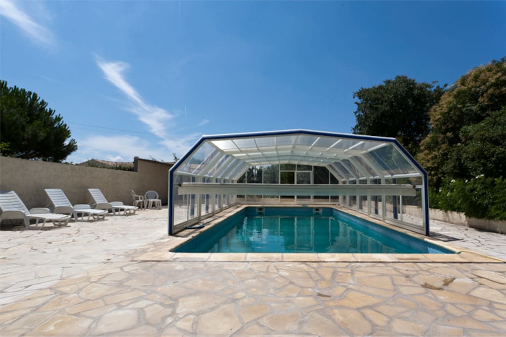 Swimming pool with retractable cover to keep water warm at extremes of season