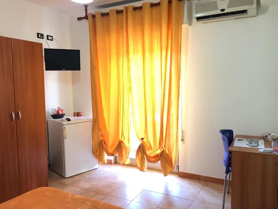 TV, scrivania, armadio e frigo. Balcone che affaccia su Via Archimede