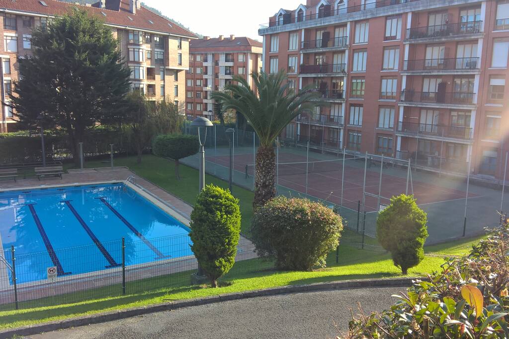 La urbanización con jardines, piscina y tenis
