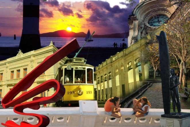 The image showcases a vibrant collage of Santos, featuring the sunset over the ocean, a historic tram, and notable buildings like the lighthouse and a clock tower. Two individuals are seen sitting on a wall, with a sculpture and lush trees in the background, reflecting the city's charm.