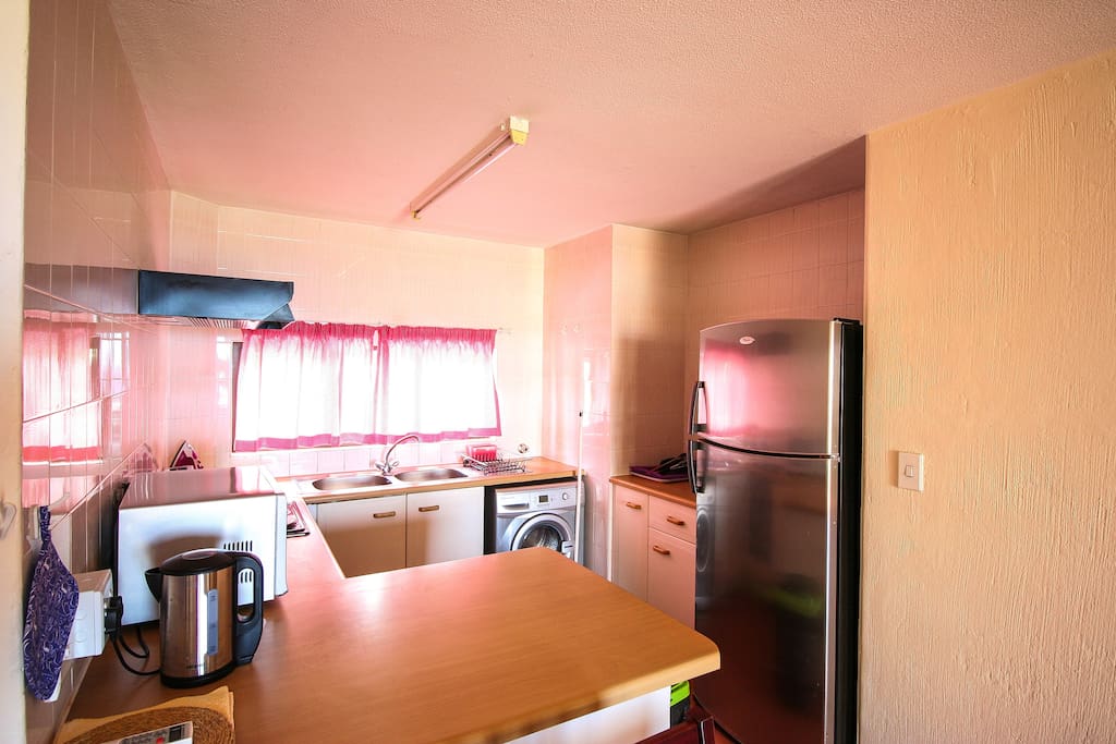 Kitchen with microwave, oven, fridge, kettle, toaster and kitchenware.