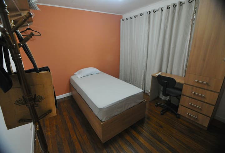 Chumba chenye starehe kwenye ghorofa ya pili, chenye kitanda kimoja, kabati la kuhifadhia, madirisha yasiyopenyeza sauti na mapazia ya kuzuia mwanga ili kupumzika vizuri. Pia ina nafasi ya dawati