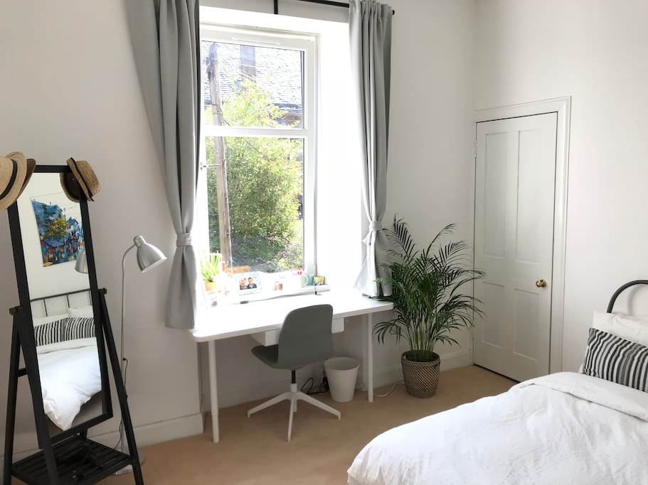 Bright bedroom with desk, mirror, hairdryer...