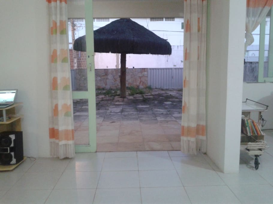 vista da parte frontal da casa, onde colocamos mesas e tem uma rede na lateral, geralmente onde sentamos pra tomar uma cerveja, conversar e é a área onde permitimos fumantes.