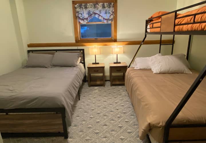 Dormitorio en el sótano n.º2 con 1 cama tamaño queen, 1 cama completa y 2 camas de una sola (la cama nido se puede sacar debajo de la cama de matrimonio). ¡Más decoración por venir! 