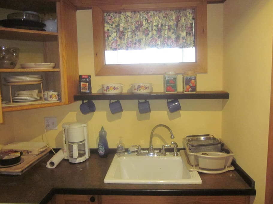 Kitchenette with deep sink, basic pantry supplies including tea and coffee, tableware, copper counter top
