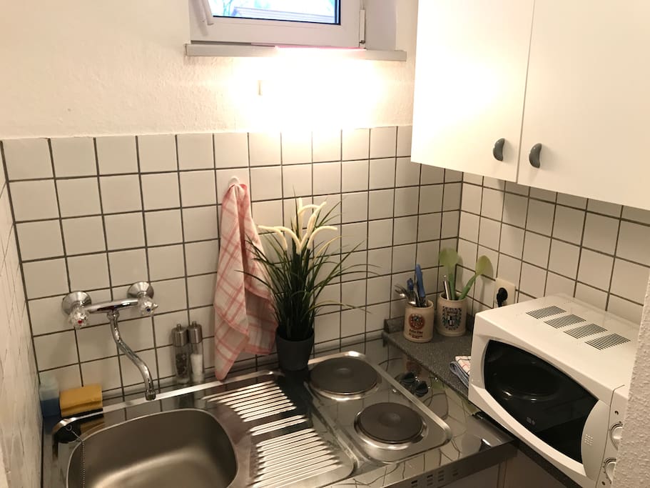 Küche mit Mikrowelle, Kühlschrank und zwei Kochplatten