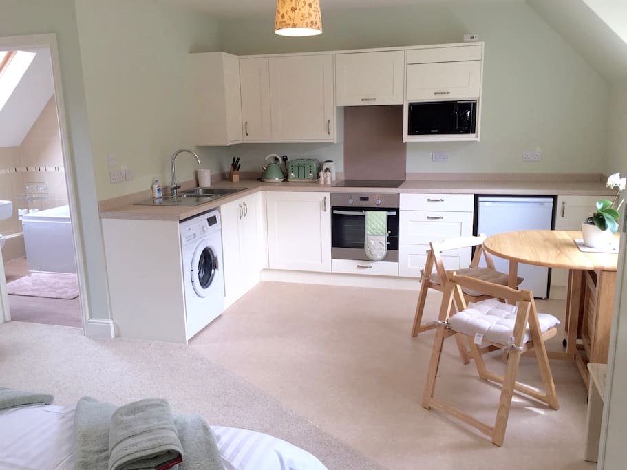 Well-equipped kitchen with extendable table and four chairs, microwave, washing machine, fridge with freezer compartment, oven with halogen hob.