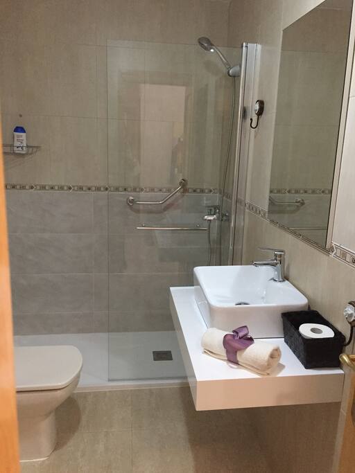 Baño con plato de ducha y mampara abatible para fácil acceso.