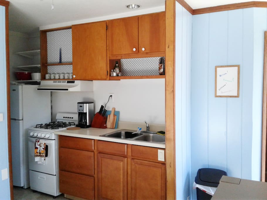 Kitchen with fridge, freezer, gas oven, coffee maker, microwave and basic cooking tools.