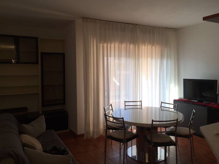 Sala con divano letto e TV con accesso alla terrazza con vista sulla piscina.