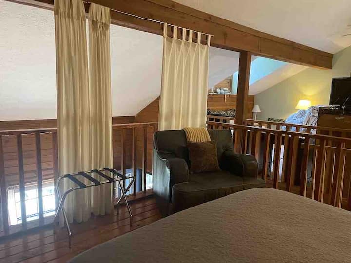 Another angle of upstairs area with sitting chair in loft bedroom as well 