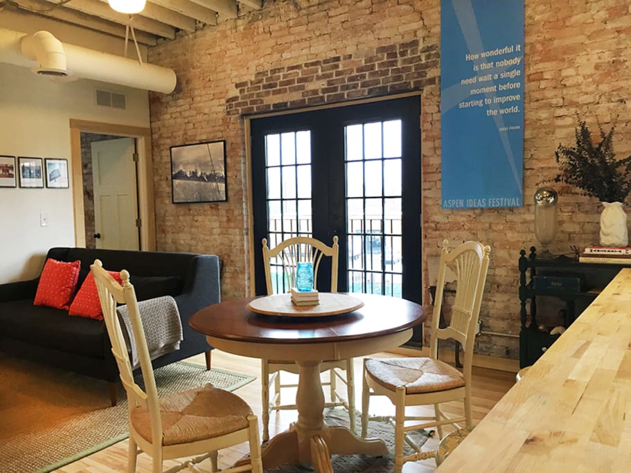 Exposed brick and a french door balcony surround the dining space.