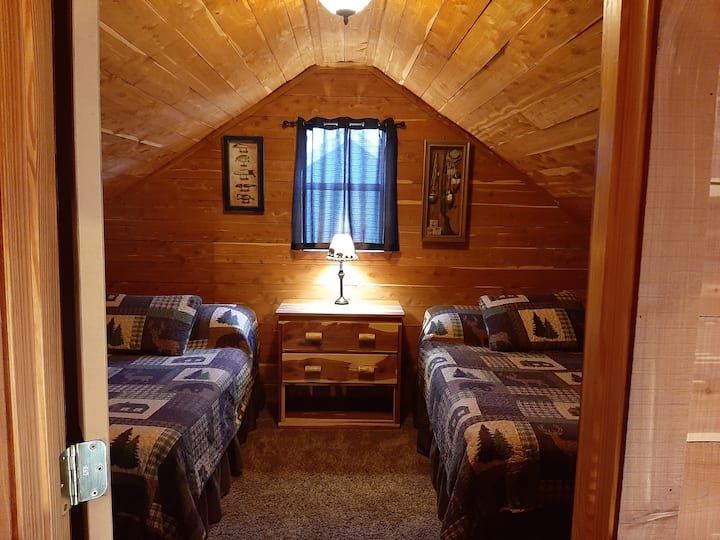 Upstairs bedroom.  Includes two full beds,  lamp,  night stand with a variety of books, dresser,  small stand for charging electronics,  fan, and additional hooks for your coats, hats, or towels.