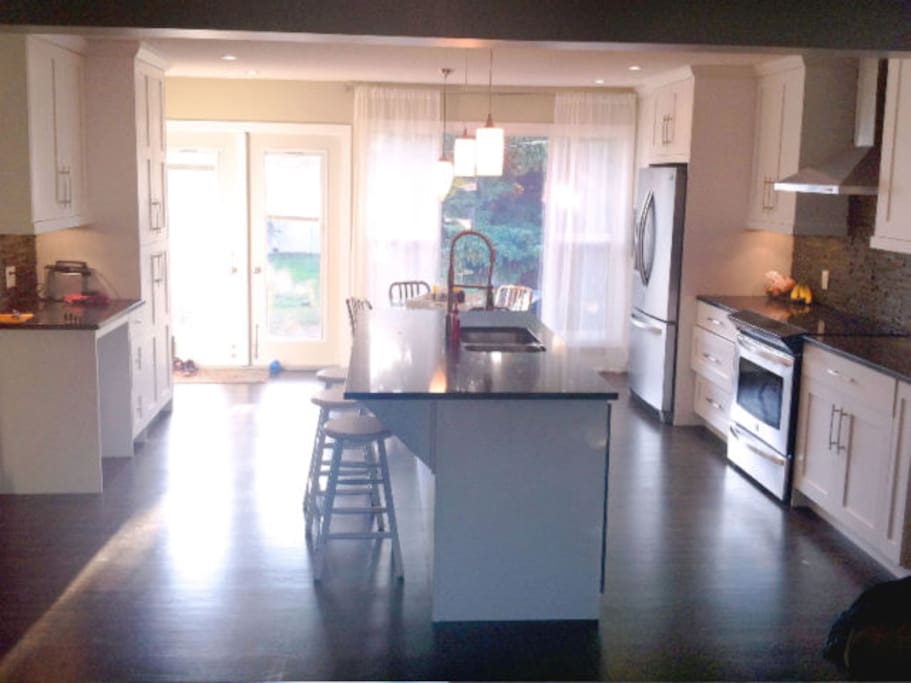 Modern kitchen which is open to the living room, and also has access to the large fenced-in backyard.