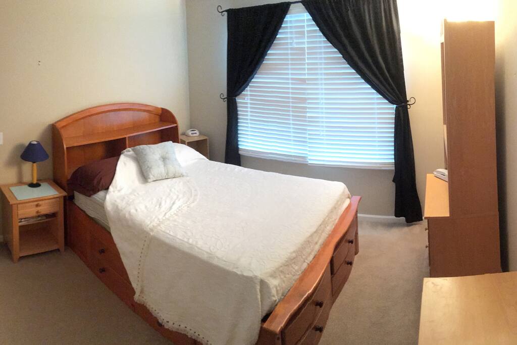 Private guest bedroom has double pillowtop platform bed, a nightstand, lowboy chest of drawers with mirror, highboy dresser with shelves, and closet.