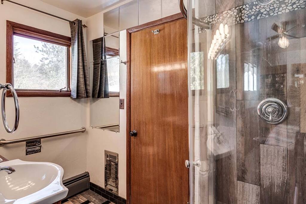 This very unique bathroom is attached. Barn wood looking tile, pebble stones, subway tile, a cute round glass enclosed shower.