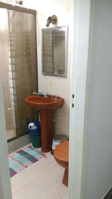 Banheiro com chuveiro elétrico e lavadora de roupas automática.