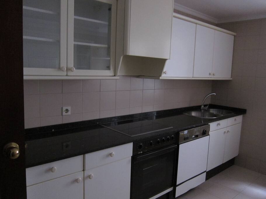 Cocina con placa vitrocerámica, lavadora, lavaplatos.