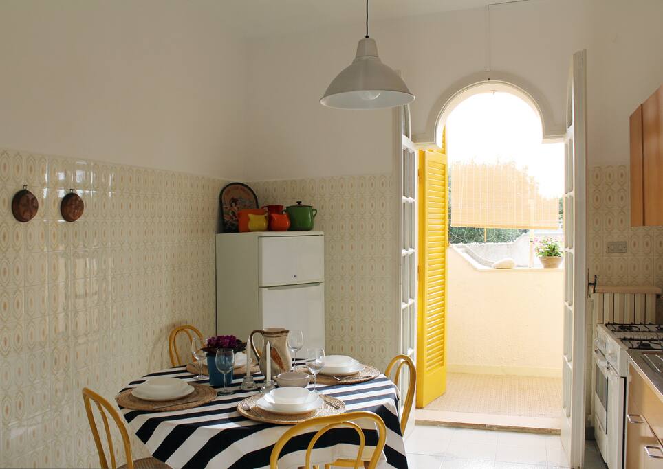 Cucina con fornelli e forno, lavatrice e pensili.