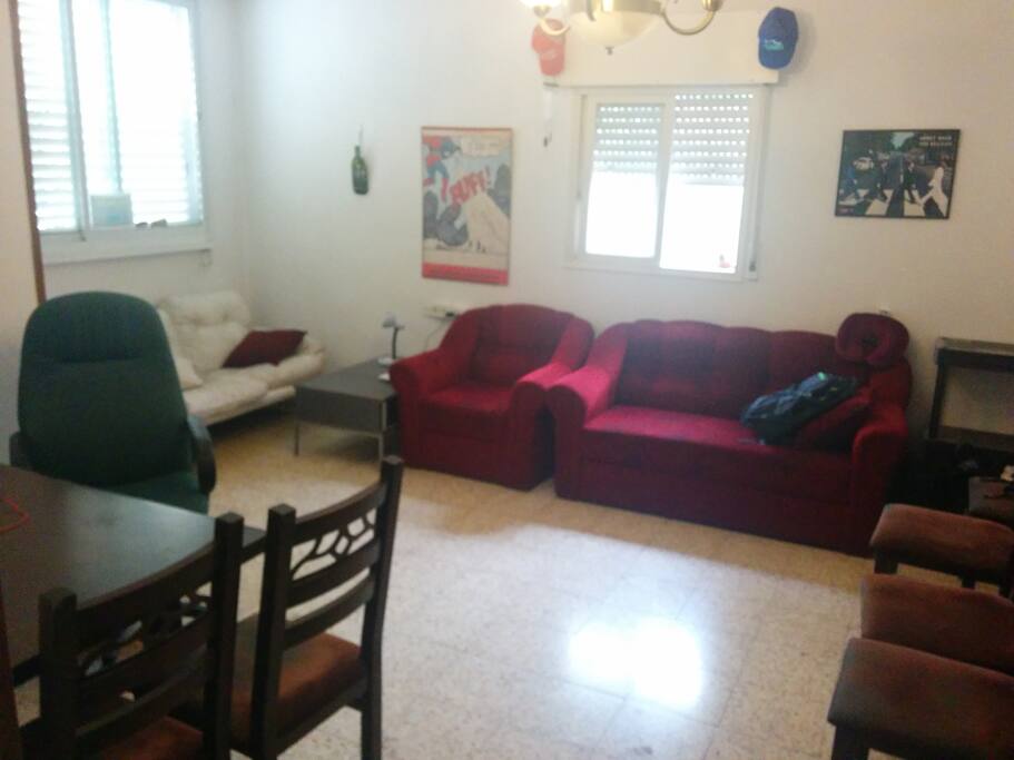 The main living room. There is a dining room table, 10 chairs, a couch and a sofa. Lots of sunlight.